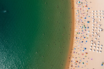 Fototapeta na wymiar Scenic view from drone of sandy beach, calm Mediterranean sea and people sunbathing