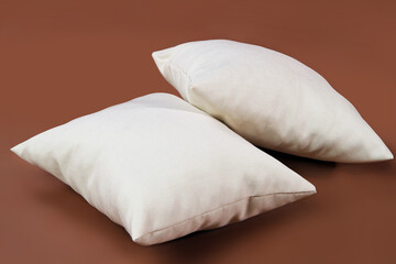 Fototapeta na wymiar Two pillows on a brown background.