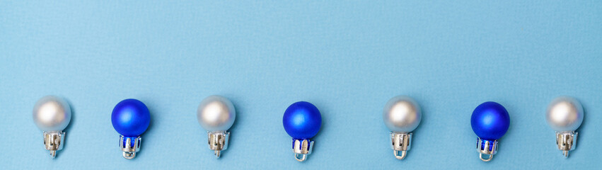 New year's composition. Christmas balls of blue and silver color lie in a row on a blue background. Flat lay, top view, copy space