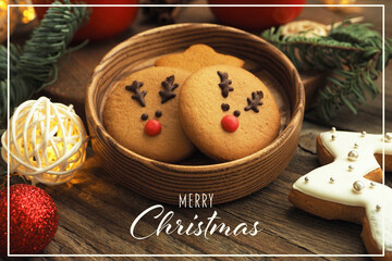 Christmas card with the inscription Merry Christmas. gingerbread cookies with deer faces, garland, Christmas tree branches and balls on a wooden table..