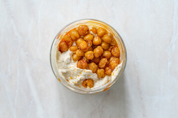 Take Away Hummus with Crispy Chickpeasi Olive Oil, Paprika and Lemon in Glass Bowl.