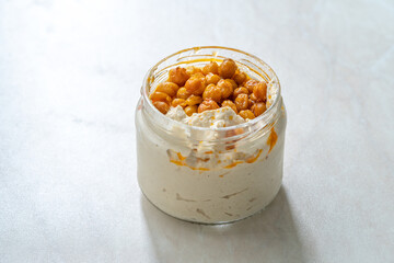 Take Away Hummus with Crispy Chickpeasi Olive Oil, Paprika and Lemon in Glass Bowl.