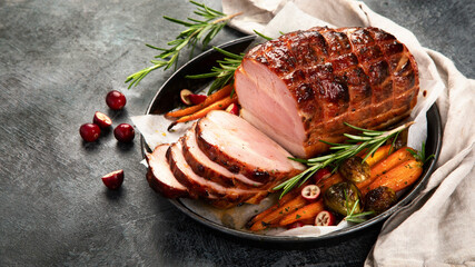 Baked ham with vegetables on dark background.