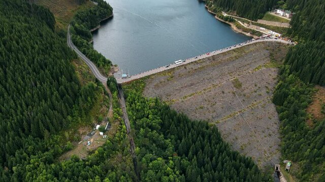 Aerial drone view of the Oasa Dam in Romania. Carpathian mountains, hills with lush forest, multiple cars