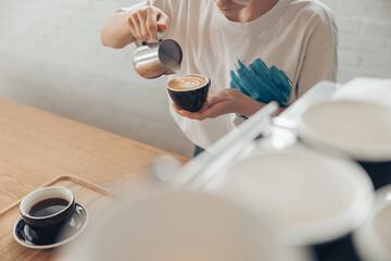 Young woman making latte art in cafeteria