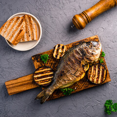 grilled dorado is served on a wooden board with vegetables