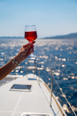 Female hand holding glass of wine on sea background