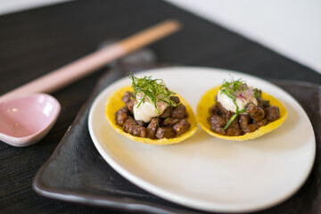 Asian style meat tartlets on white plate with wooden chopsticks on black mat in Japanese restaurant. close up, photo for the menu
