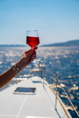 Female hand holding glass of wine on sea background