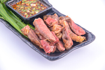 Roasted pork steak on the black plate with thai sauce.