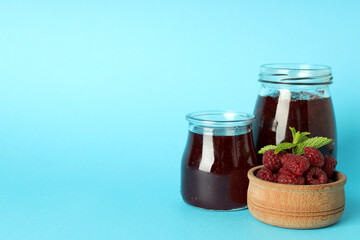 Jars of raspberry jam with ingredients on blue background