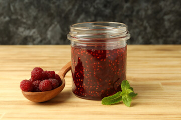 Jar of raspberry jam with ingredients on wooden table