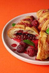 Plate with croissants with raspberry jam on orange background