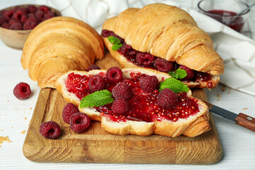 Concept of delicious food with croissants with raspberry jam on white wooden background