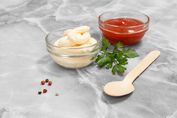 Glass bowls with ketchup and cheese sauce on kitchen table.