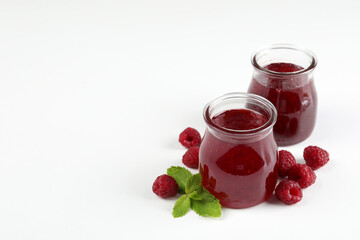 Jars of raspberry jam with ingredients on  white background