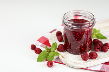 Jar of raspberry jam with ingredients on white wooden stand