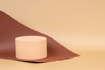 Abstract creative composition with empty round podium platform for product presentation and curve shaped torn brown paper edges on pastel beige background. Front view