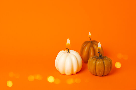 three burning pumpkin candles on an orange background. halloween, thanksgiving, harvest festival concept