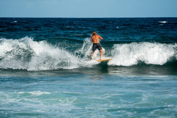 male surfer doing a turn on a wave at the beach in summer on a sunny day