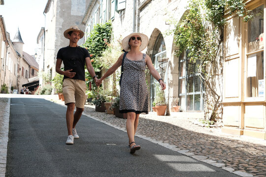 Smiling couple holding hands walking down the street, Carennac, Quercy, Lot, Occitanie, France