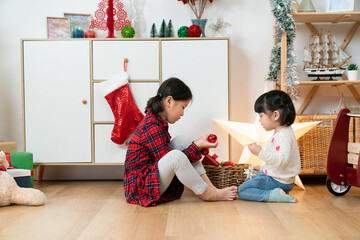 side view of two asian female children enjoying playing with Christmas decors together in the living room at home during xmas holiday
