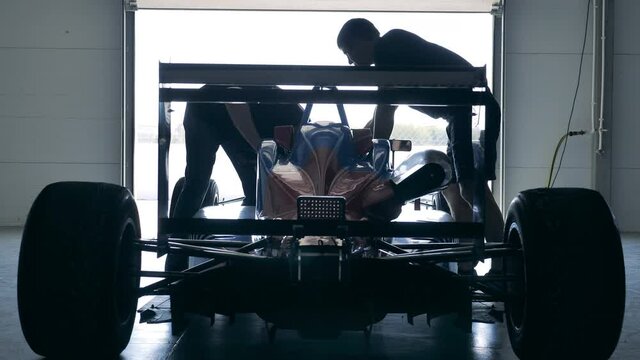 Racing car is getting checked by two mechanics