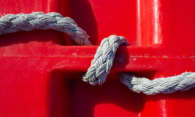 Marine red background. Detail of a plastic float with a white rope.