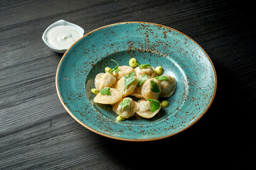 Chinese dumplings stuffed with meat with white sauce in a blue plate on a wooden background