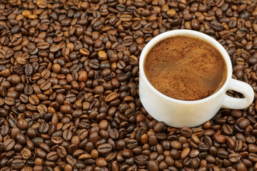 Cup of coffee on the background of roasted coffee beans.