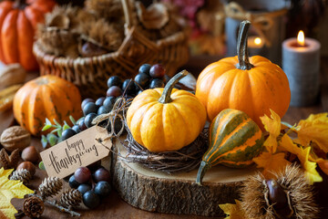 Happy Thanksgiving greetings - beautiful pumpkin composition with grapes, lit candles, chestnuts, fall decorations and a greeting card