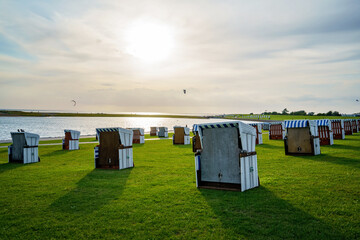 Traditional German roofed wicker beach chairs on the beach of North Sea, Nordsee, Germany, Wattenbeer. Beach with relax chairs on stormy sunny day.