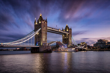 Long exposure view of the lifted Tower Bridge in London with a ship passing by during evening time