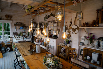 Fototapeta na wymiar Beautiful arrangement of wooden decor and ceramic decoration in a shop for indoor, outdoor and garden. Light bulb as fairy lights.