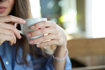 Small white cup in the women fingers close up picture horizontal orientation 