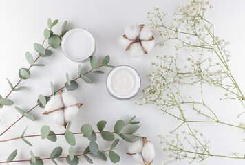 cream on white background with eucalyptus and cotton flower