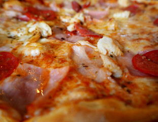 pizza close-up with cheese, pepperoni, bacon and chicken pieces. side view