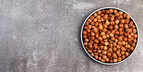 Hazelnuts on a round plate on a dark background. Top view, flat lay
