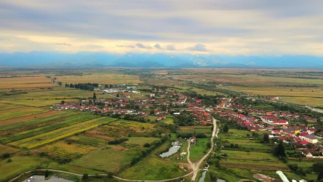 Aerial drone view of Carta, Romania. Country buildings, greenery, Carpathian mountains on the background