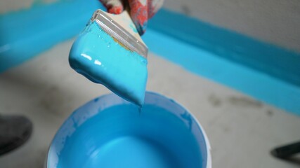 A worker paints a waterproof finishing material with a brush. The bathroom floor in the apartment...