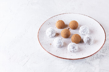 Truffles in cocoa powder and dry coconut milk on a plate. Sugar, gluten and lactose free, vegan.