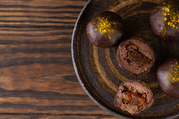 Chocolate truffles with orange filling on a plate. Horizontal orientation, top view, copy space. Sugar, gluten and lactose free.