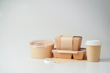 Empty craft paper disposable food boxes nearby cup and coffee cup with mock-up on white background. Delivery food concept.