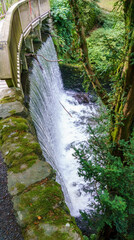 a wooden bridge over a waterfall at Bodnant Gardens, Tal-y-Cafn, Conwy, Wales, UK