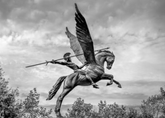 Bellerophon riding winged horse pegasus spear in hand dark sky moody, trees black and white