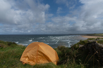 Little orange tent on the edge of the cliff