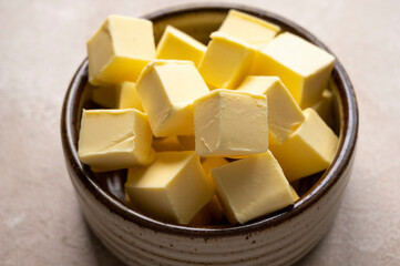 Butter cubes in bowl, rustic warm background. Dairy product