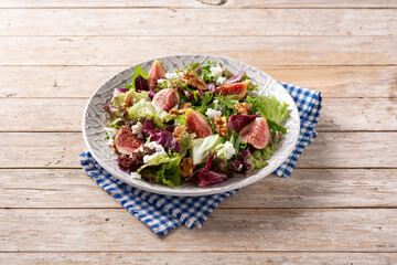 Figs salad with cheese and walnuts on wooden table.