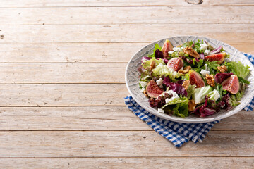 Figs salad with cheese and walnuts on wooden table. Copy space