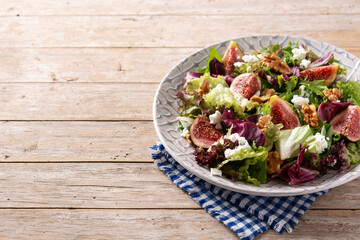 Figs salad with cheese and walnuts on wooden table. Copy space